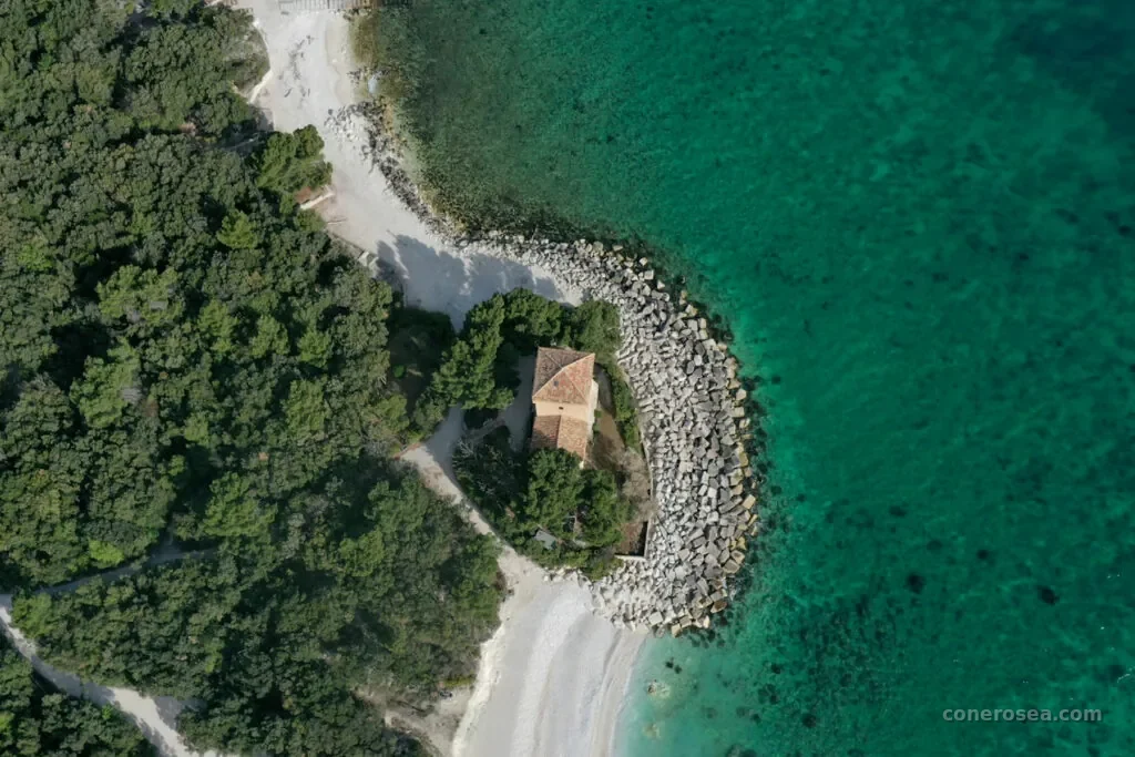 Veduta aerea della costa del Conero con un eremo immerso nel verde affacciato sul mare