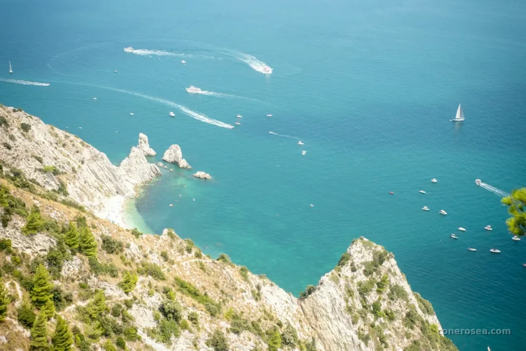 Veduta dall'alto dei faraglioni delle Due Sorelle e delle barche nelle acque turchesi del Conero