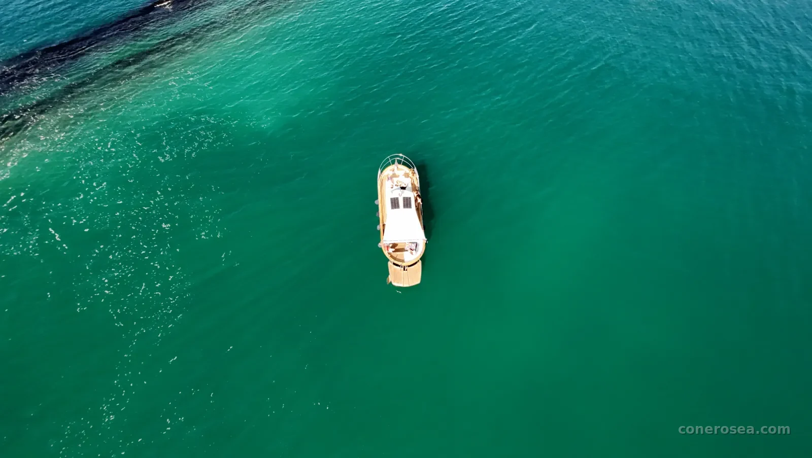 La barca di Conero Sea ripresa dal drone direttamente dall'alto mentre scivola sulle acque verde smeraldo del Conero