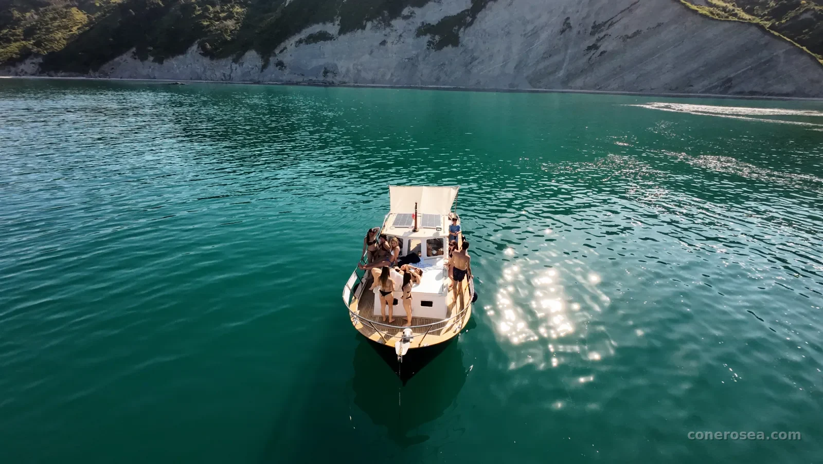 La barca con gli ospiti a bordo all'ancora sotto le bianche falesie del Conero, vista dal drone