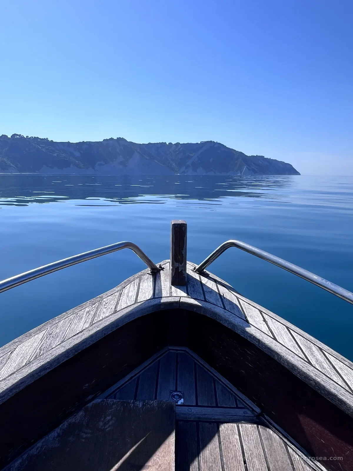 La prua della barca punta verso il promontorio verde del Monte Conero