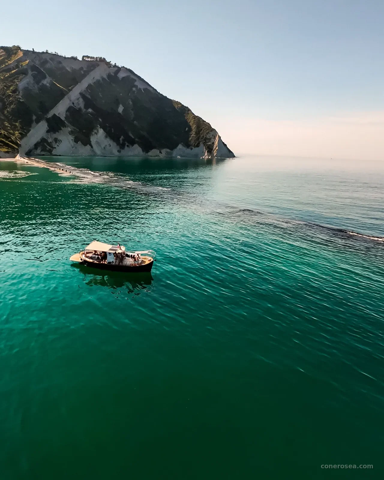La barca di Conero Sea all'ancora nelle acque verde smeraldo ai piedi delle falesie del Monte Conero