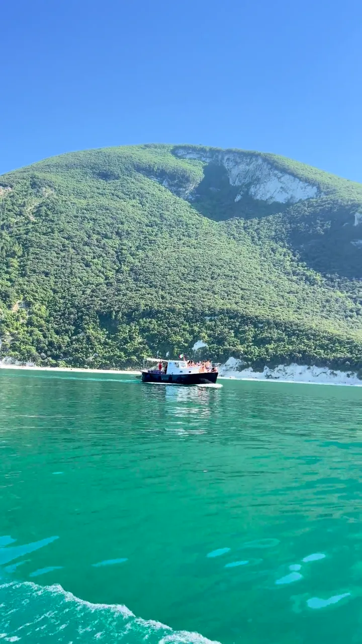 La barca di Conero Sea naviga sotto le falesie verdi del Conero lungo la costa