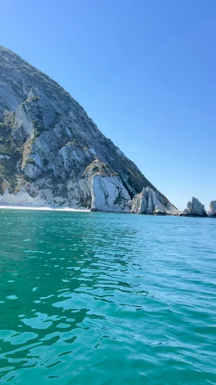 I faraglioni delle Due Sorelle e la barca sulle acque turchesi del Conero