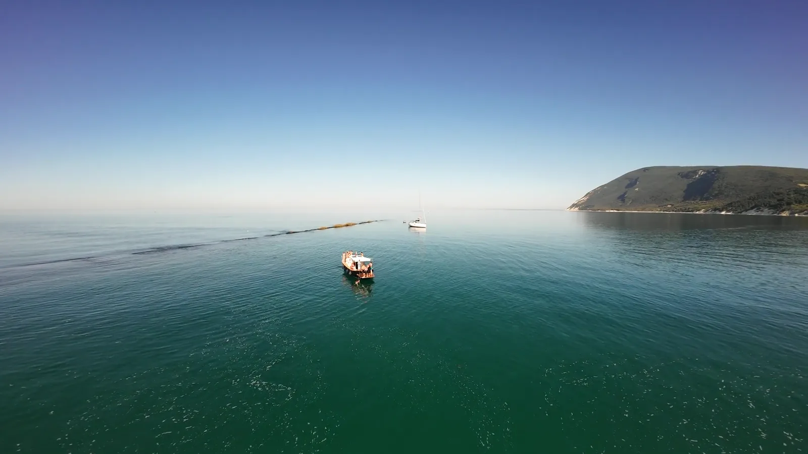 Veduta aerea della Riviera del Conero con la barca sulle acque verde smeraldo